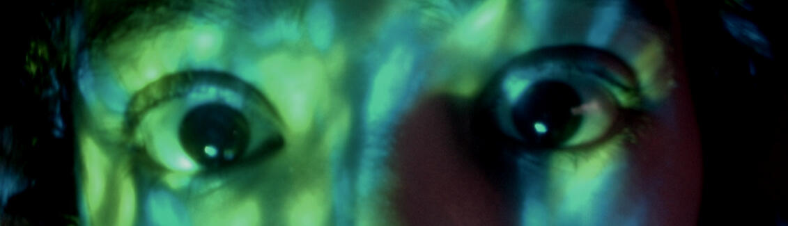 a photo of two big brown eyes staring at your soul. there are some green and blue lights/shades on top of their face.